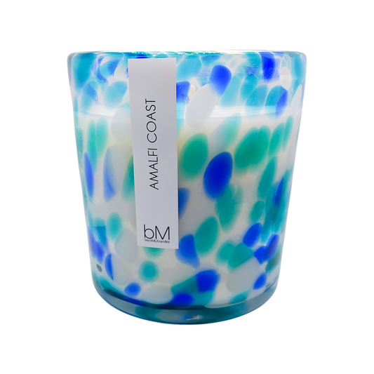Candle with blue and green pattern and 'Amalfi Coast' label on a white background